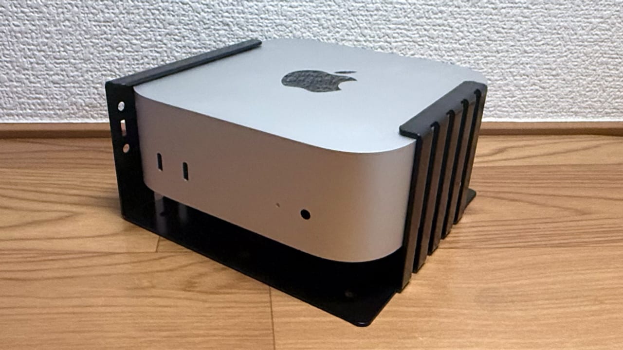 对 Nagao Seisakusho Mac mini 2024 安全支架的评论，它可以让您将 Mac mini (2024) 固定到符合 VESA 的显示器背面或桌子下方，还可以更轻松地按下底部的电源按钮。